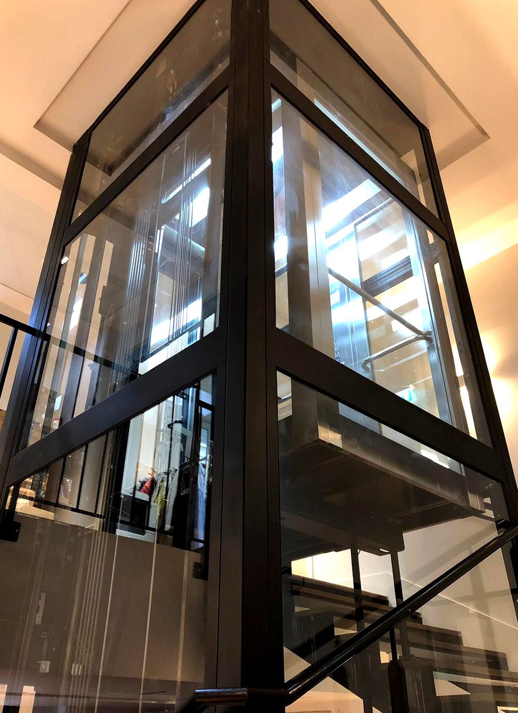 Ascensor con estructura modular y cristal transparente instalado en un edificio existente